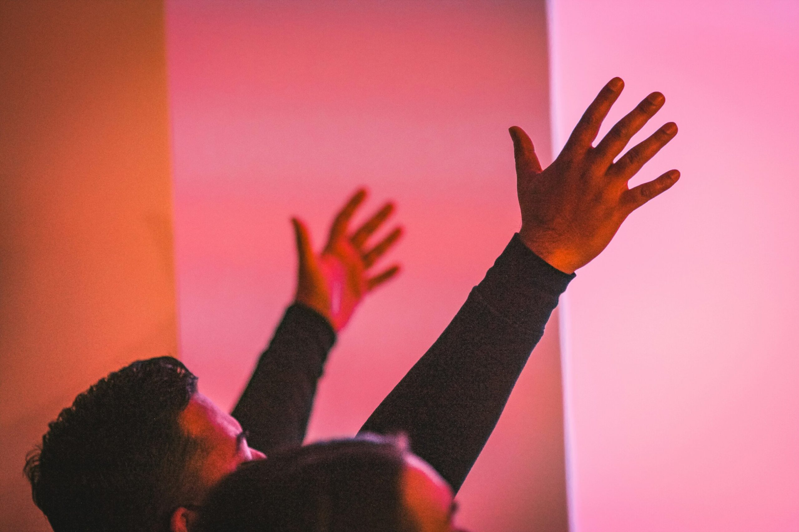 An image of a man raising his hands in surrender and worship to Jesus.